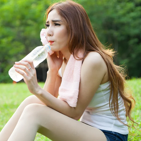 Kobieta siedząca zmęczony i wody pitnej po wysiłku. — Zdjęcie stockowe