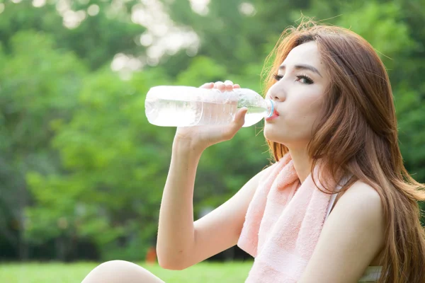 Femme assise fatiguée et buvant de l'eau après l'exercice . — Photo