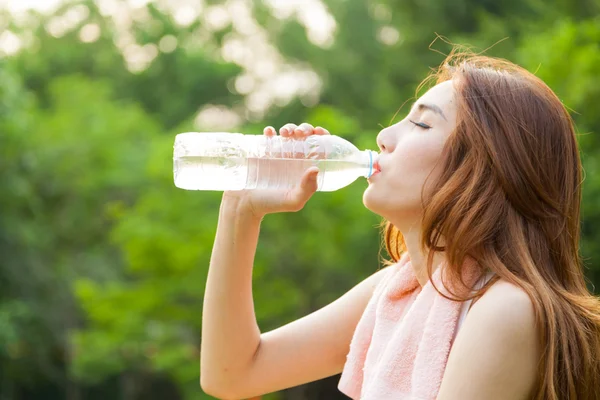 Woman sitting tired and drinking water after exercise. — Stock Photo, Image