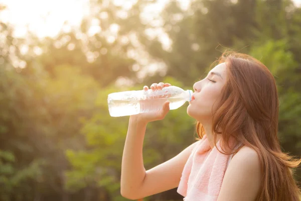 Vrouw zitten vermoeid en drinkwater na uitoefening. — Stockfoto