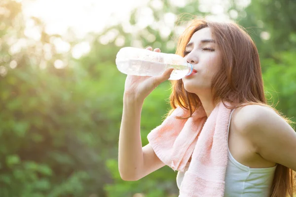 Mujer sentada cansada y bebiendo agua después del ejercicio . —  Fotos de Stock