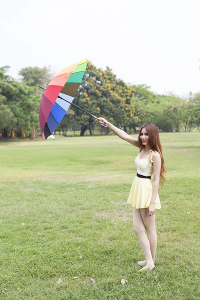 Žena s deštníkem stojí na trávníku. — Stock fotografie