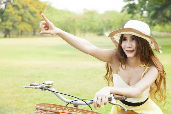 Woman sitting on the bike and pointing forward. — Stock Photo, Image