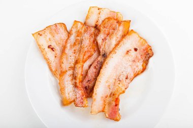 Kızarmış domuz pastırması beyaz tabakta pizzaya eklenecek.