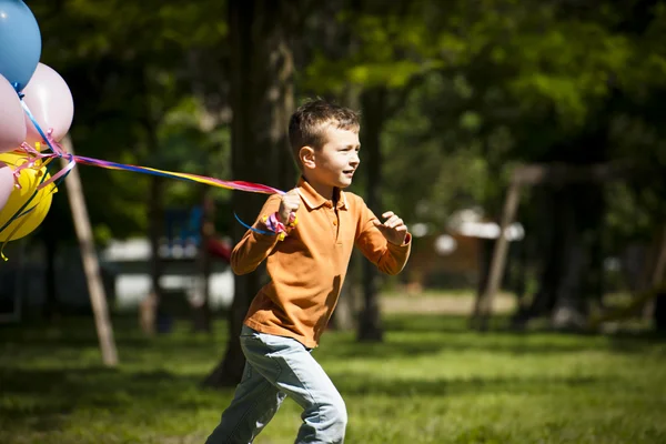 Little boy running with balloons — Stock Photo, Image