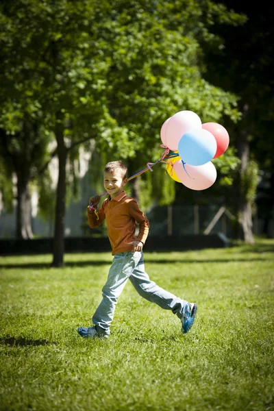 Liten pojke kör med ballonger — Stockfoto