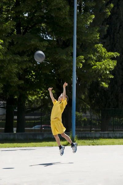 Pieni poika pelaa koripalloa — kuvapankkivalokuva