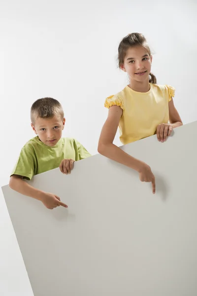 Dos niños sosteniendo un cartel en blanco — Foto de Stock