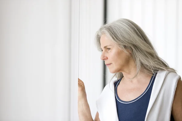 Portrait of senior woman a the window — Stock Photo, Image