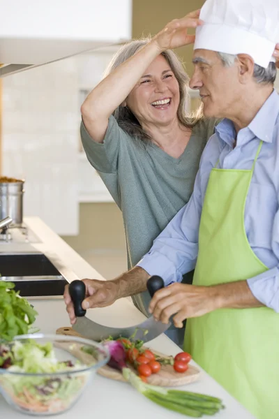 Äldre par spela medan matlagning — Stockfoto