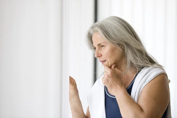 Portret van senior vrouw een het venster — Stockfoto