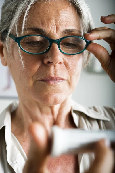 Senior woman reading medicine — Stock Photo, Image