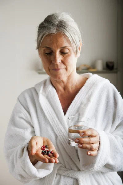 Mujer mayor con pastillas y agua —  Fotos de Stock