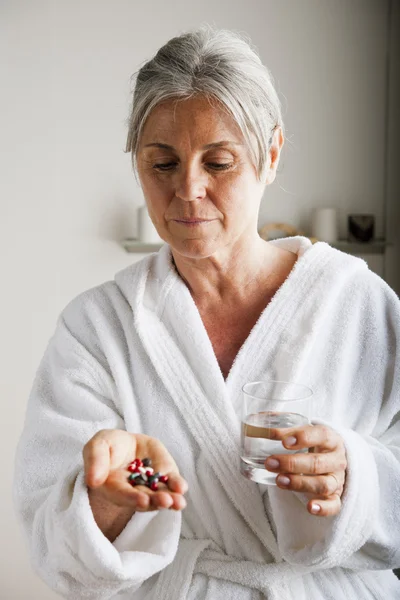 Senior woman with pills and water — Stock Photo, Image