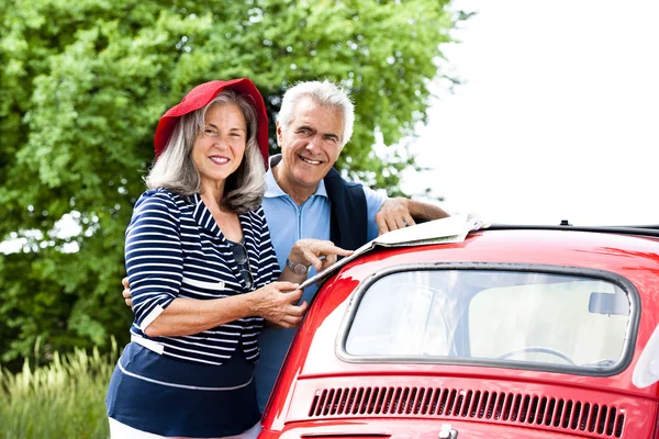 Casal sênior com carro vintage — Fotografia de Stock