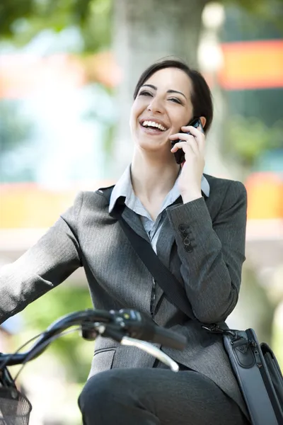 Empresária de bicicleta e falando ao telefone — Fotografia de Stock