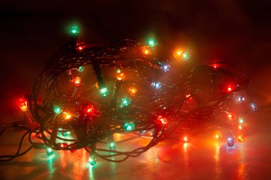 Karanlık bir arka planda sislerde parlayan çelenkler.