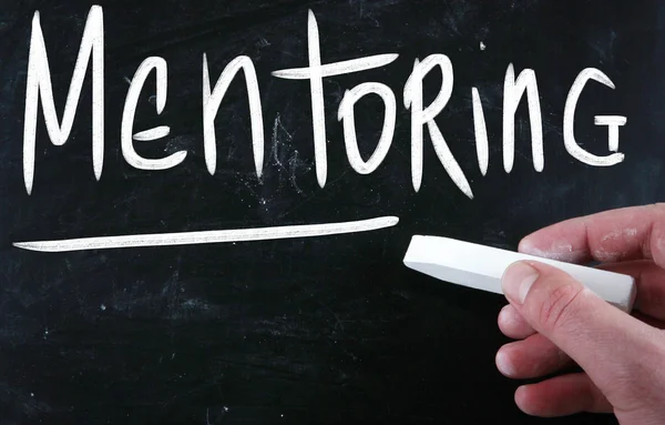 Le mot "mentorat" écrit à la main avec de la craie blanche sur un tableau noir — Photo