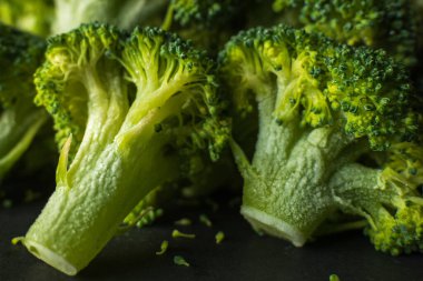 Koyu arkaplanda donmuş yeşil brokoli çiçekleri.