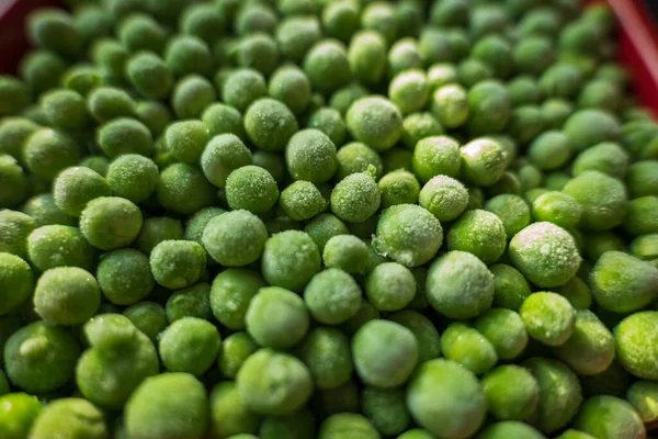 Pois verts gelés congelés dans un bol en céramique rouge gros plan — Photo