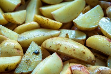 Yağ ve baharatla karıştırılmış taze çiğ patatesler yakın çekim için hazır..
