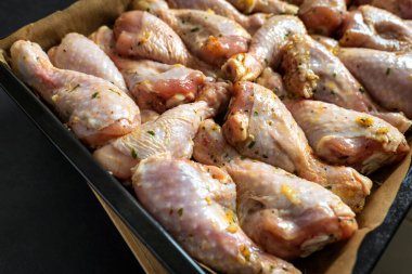 Pişirme tepsisindeki çiğ tavuk budu fırın için hazır.