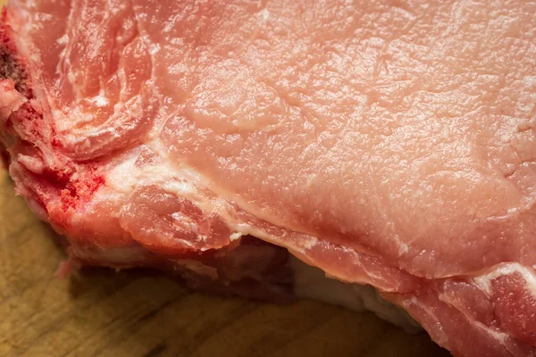 Свежая сырая свиная отбивная на деревянной доске крупным планом — стоковое фото