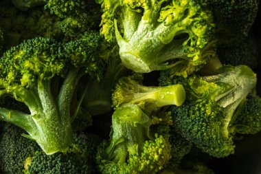 Koyu arkaplanda donmuş yeşil brokoli çiçekleri.