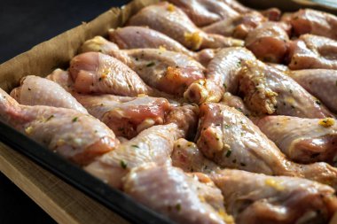 Pişirme tepsisindeki çiğ tavuk budu fırın için hazır.