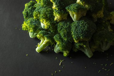 Koyu arkaplanda donmuş yeşil brokoli çiçekleri.