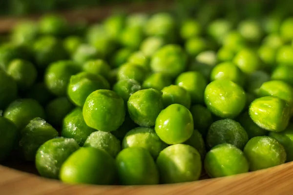 Frysta frostiga gröna ärtor på trä tallrik närbild — Stockfoto