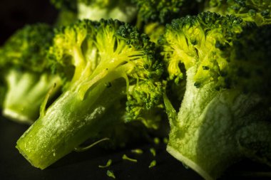 Koyu arkaplanda donmuş yeşil brokoli çiçekleri.