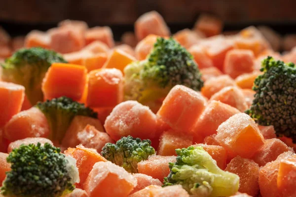 Cenouras congeladas brócolis peças close-up fundo — Fotografia de Stock