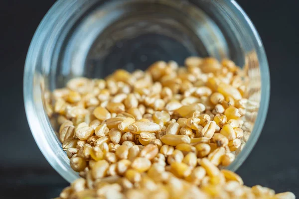Зерно пшениці, що виливається зі скла крупним планом — стокове фото