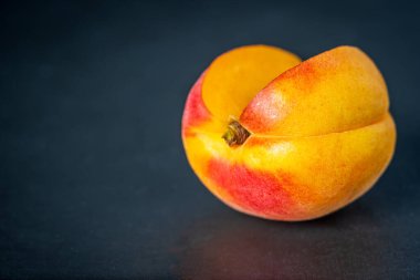 Olgun tek kayısı meyvesi koyu arkaplanda kesilip açılmış..