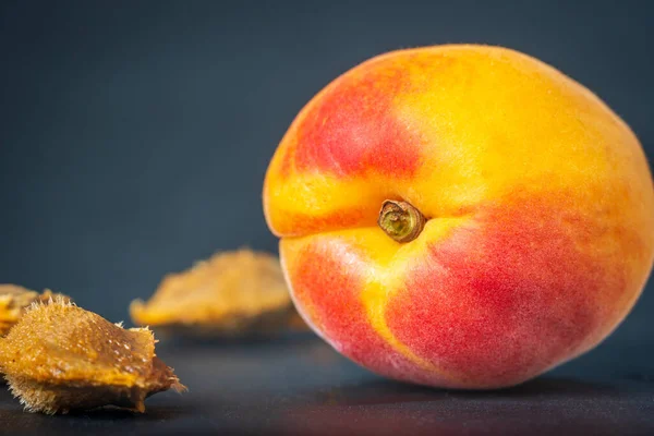 Ripe single apricot fruit with stone seed over dark background closeup.