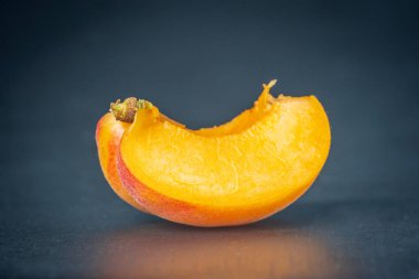 Olgun, tek bir kayısı dilimi koyu arkaplanda kesilip açılmış..