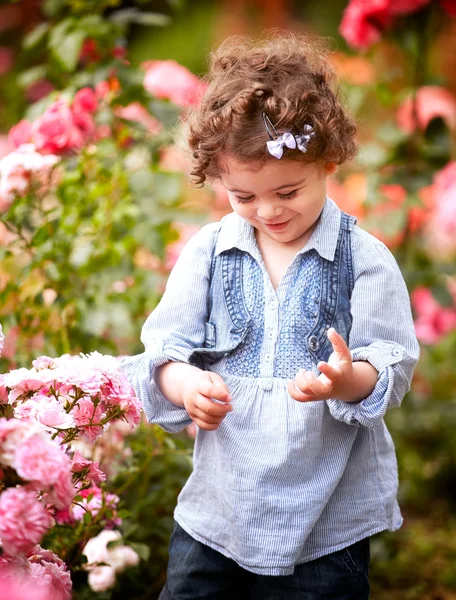 Meisje van de baby in de rozentuin — Stockfoto