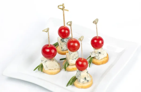 Canapés em uma chapa com queijo e tomates de cereja — Fotografia de Stock