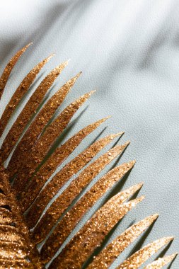 Mavi duvarda altın palmiye yaprakları ve gölgeler.