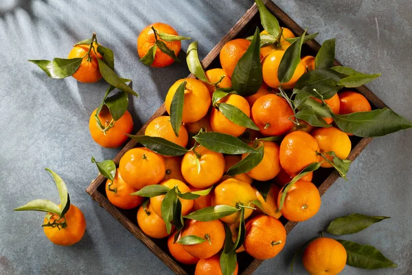 stock image Fresh mandarin oranges fruit with leaves in wooden box, top view.