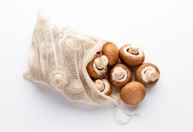 Taze Şampiyon mantarları beyaz arka planda eko pamuk torbaları. 