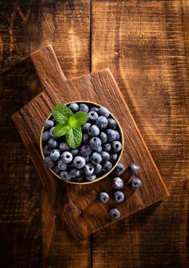 Köy tahtasında bir kase taze yaban mersini. Sağlıklı yaşam tarzı için organik yiyecek yaban mersini ve nane yaprağı..