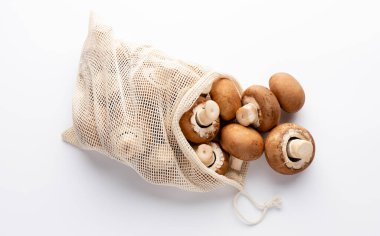 Taze Şampiyon mantarları beyaz arka planda eko pamuk torbaları. 