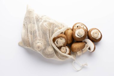 Taze Şampiyon mantarları beyaz arka planda eko pamuk torbaları. 