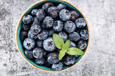 Beton masasında yeşil nane yapraklı taze yabanmersini.. 
