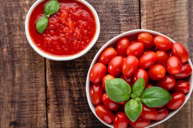 Tabaktaki taze domatesler ahşap masada. Domates arka planı, sağlıklı sebze ve fesleğen yaprakları..