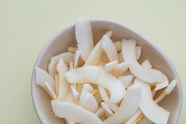 Hafif arkaplanda lezzetli hindistan cevizi parçacıkları olan kase.