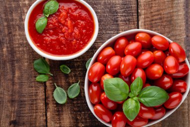 Tabaktaki taze domatesler ahşap masada. Domates arka planı, sağlıklı sebze ve fesleğen yaprakları..