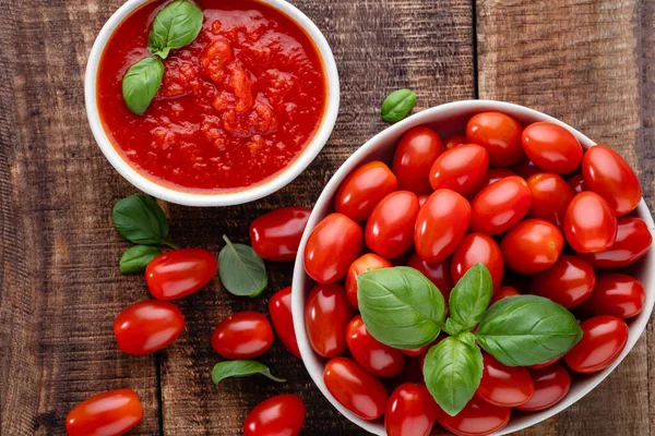 Tabaktaki taze domatesler ahşap masada. Domates arka planı, sağlıklı sebze ve fesleğen yaprakları..